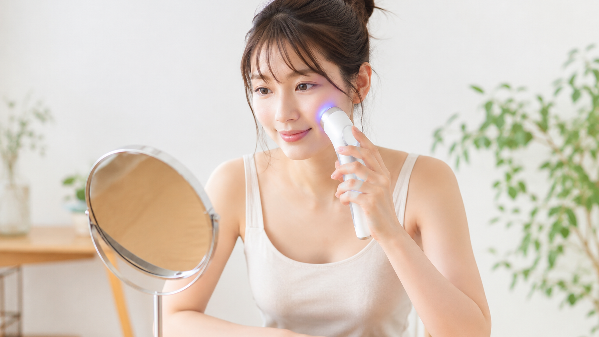 卓上ミラーの前で照射レベルを確認しながらセルフケアする若い女性