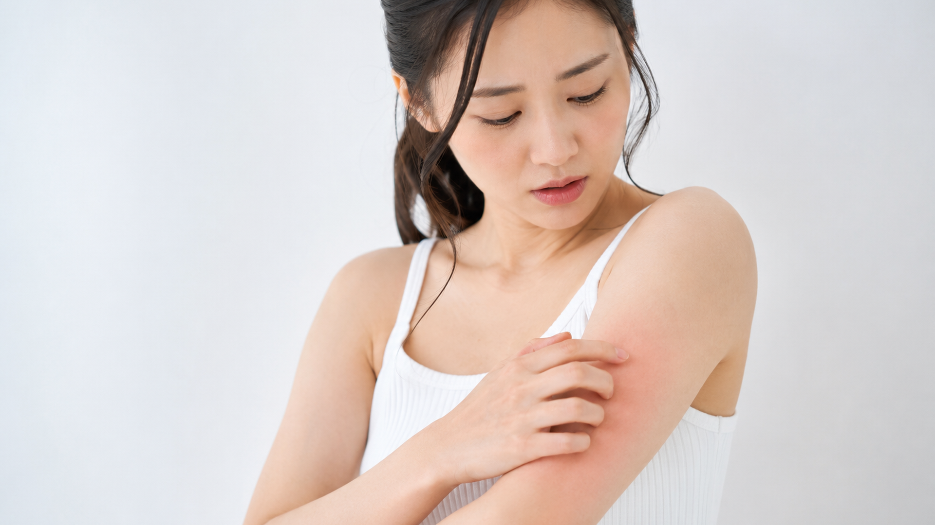 腕に赤みが出て手で触れている女性の様子